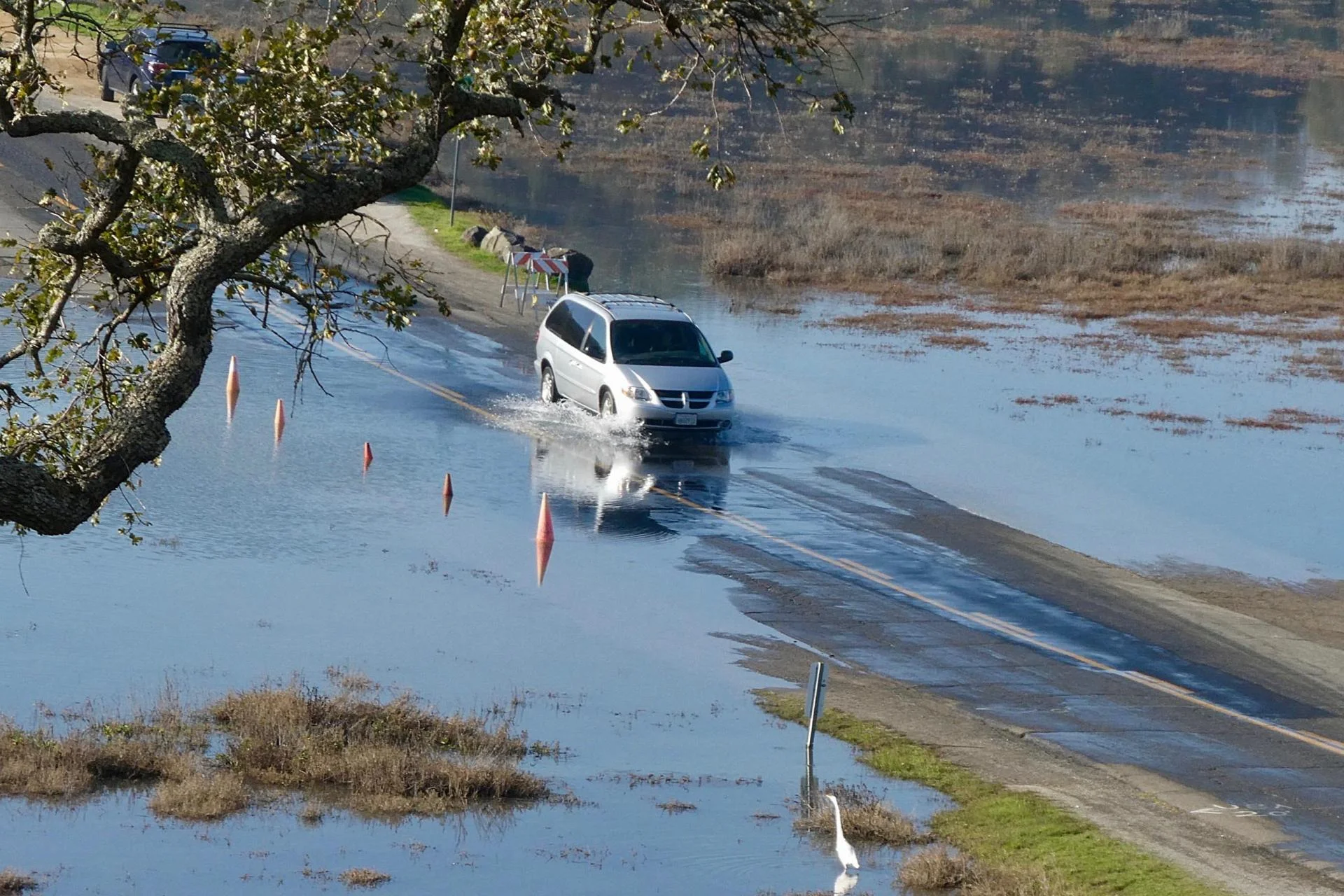 Car driving over flooded road.
