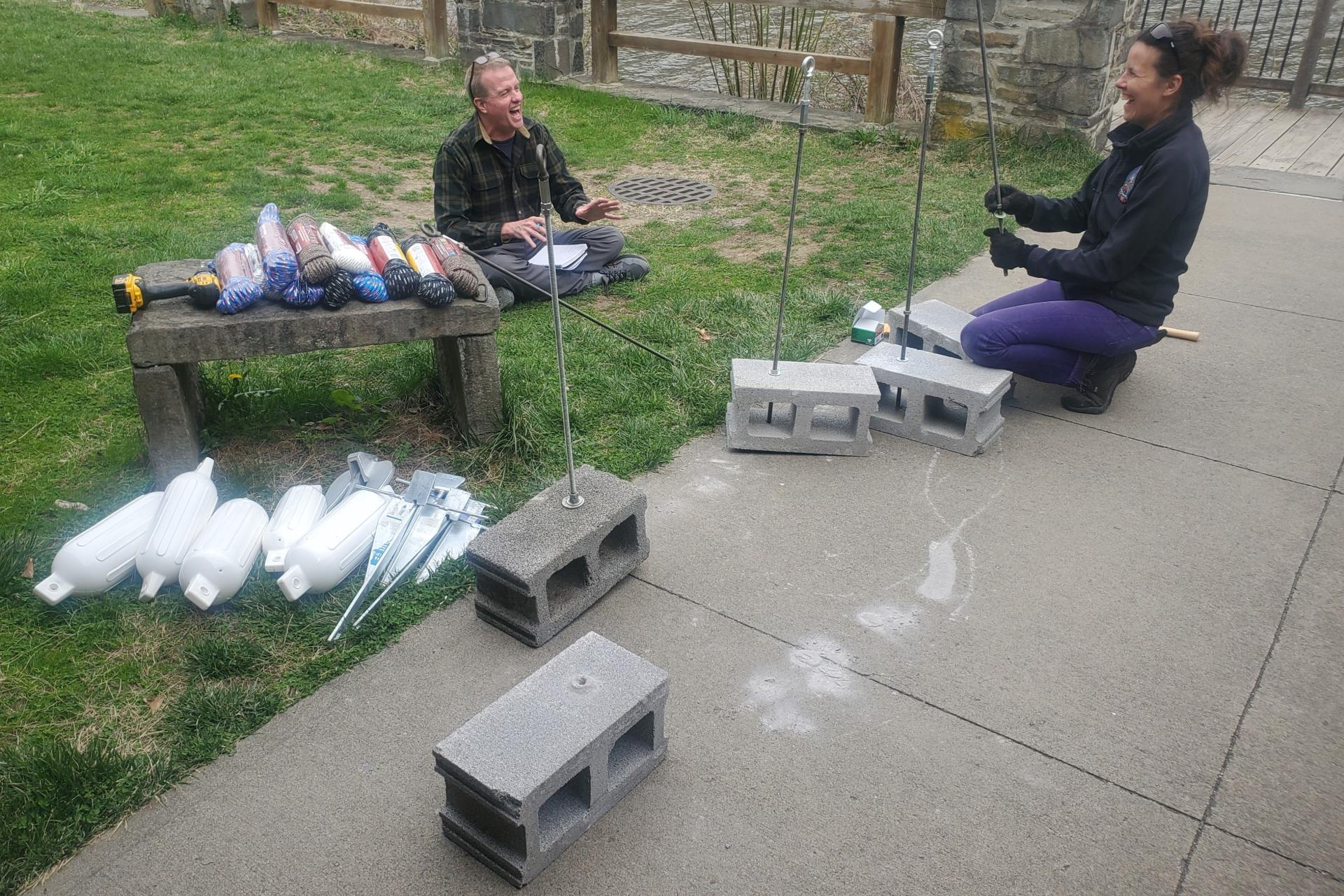 People placing rods into cement blocks.