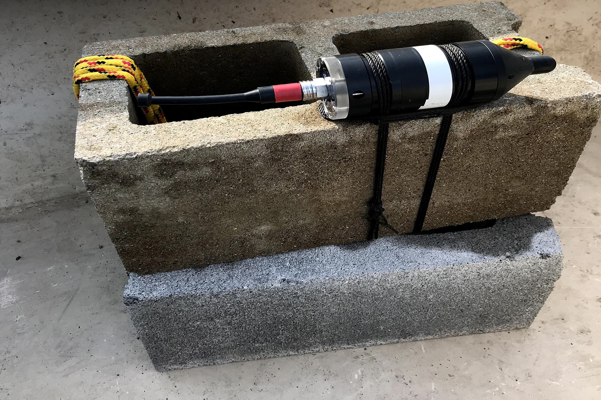 Acousting monitoring device attached to a cinder block 
