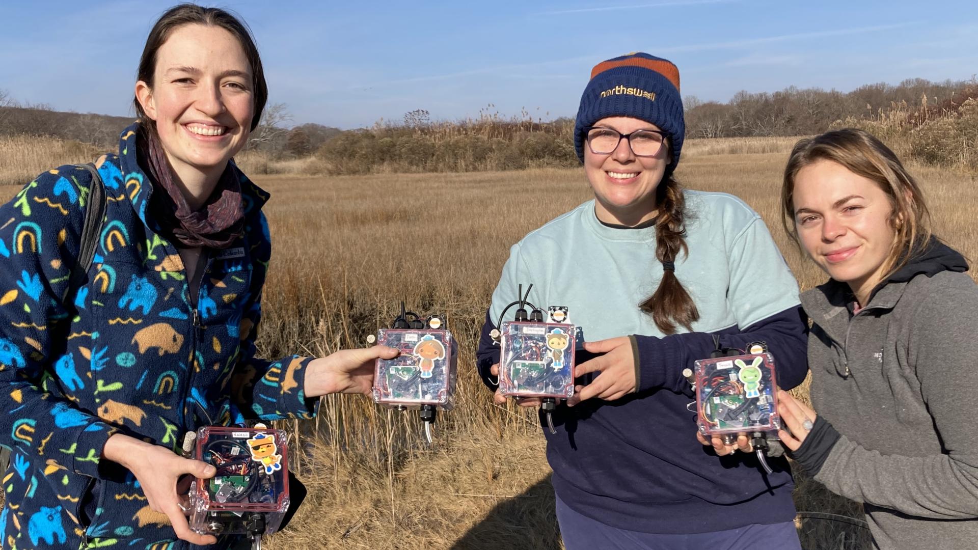 Three people holding sensor boxes