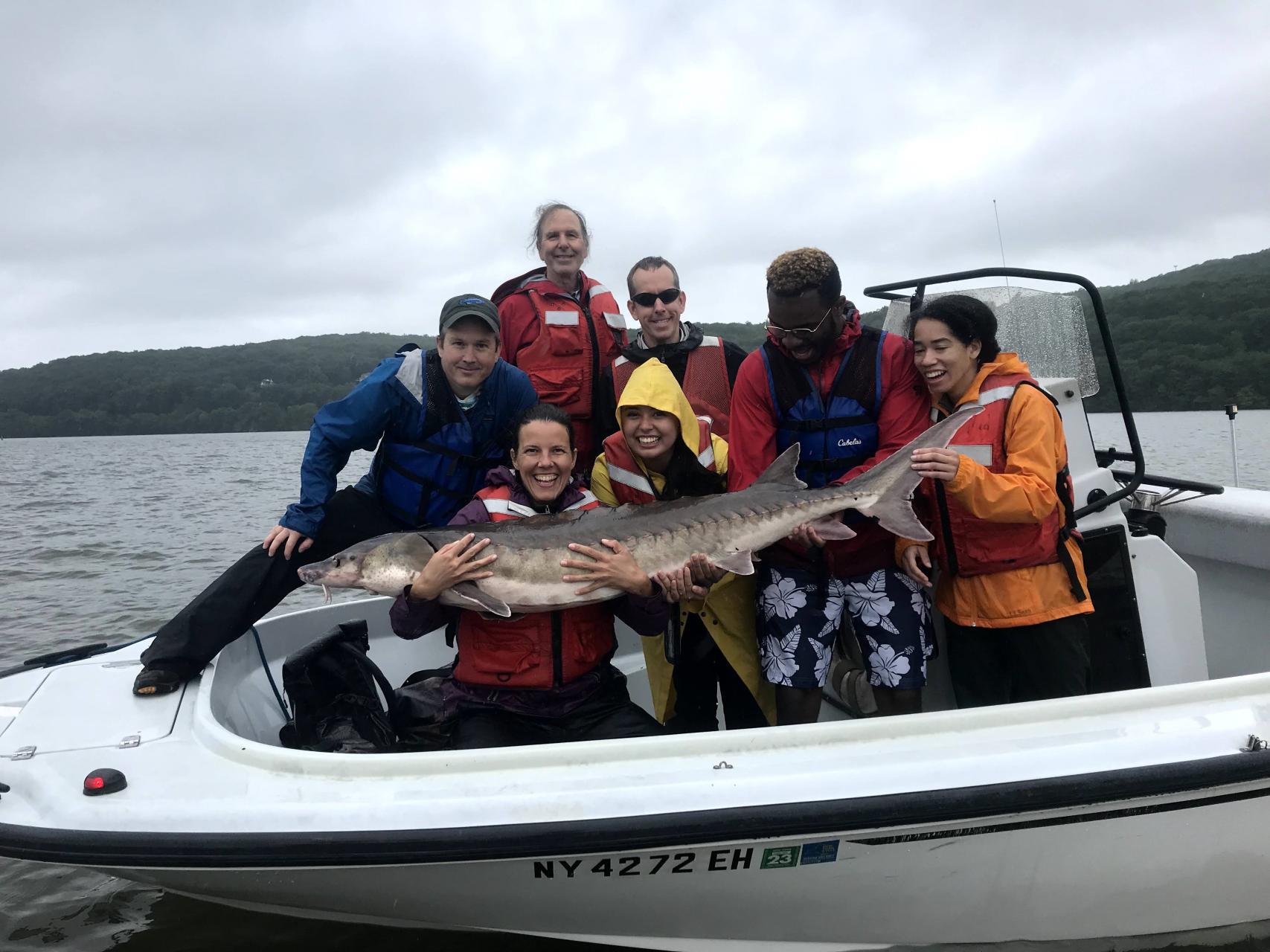 Group of people with large sturgeon on boat