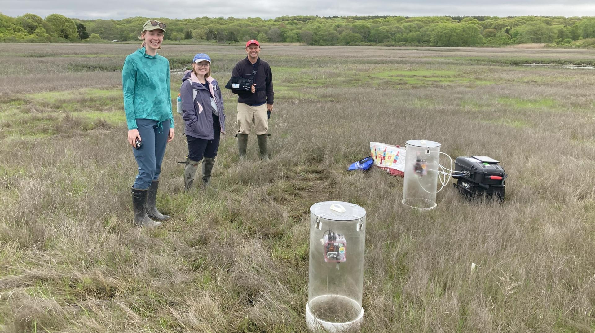 Three people standing in a grass field