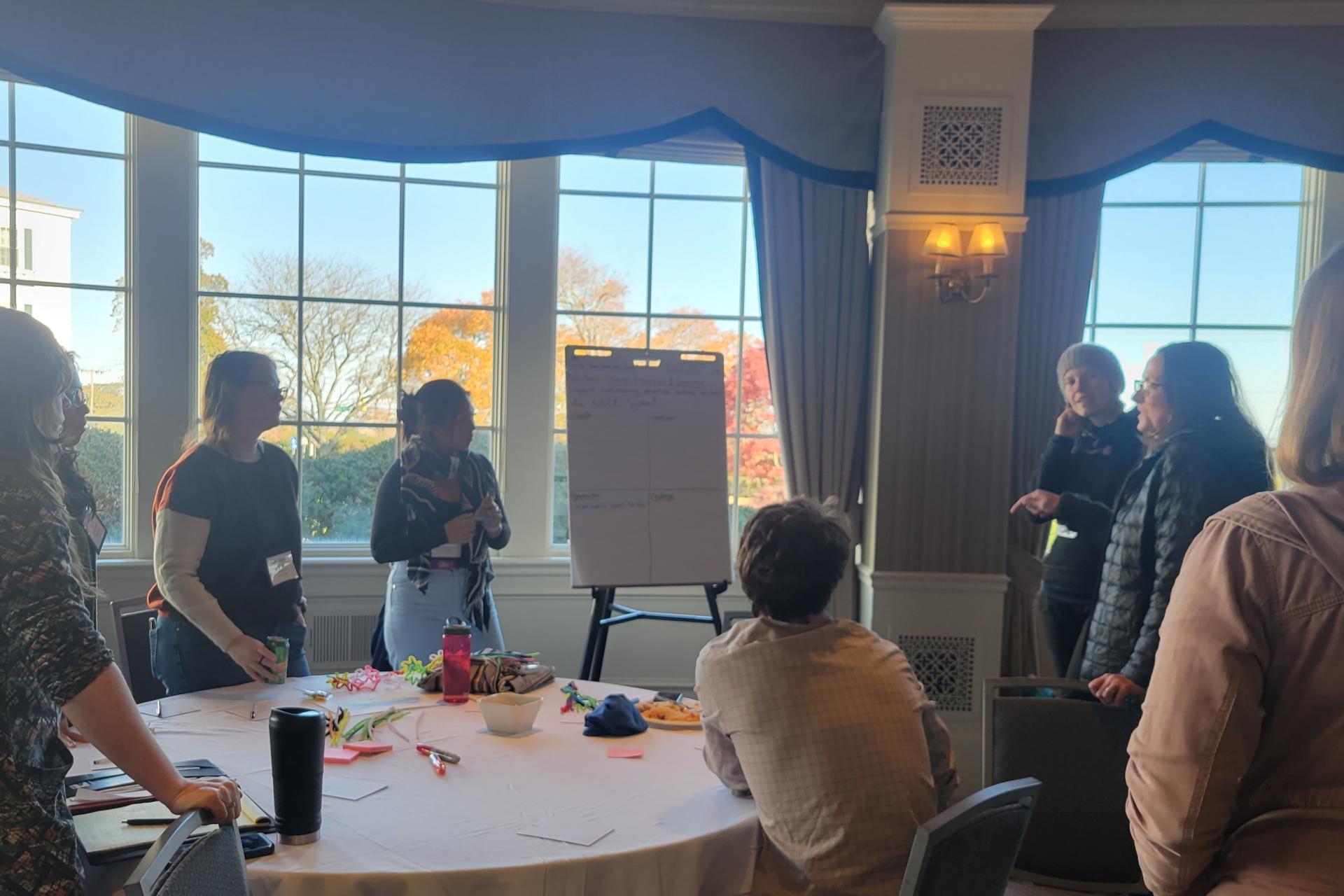 People standing around a table and looking at a whiteboard.