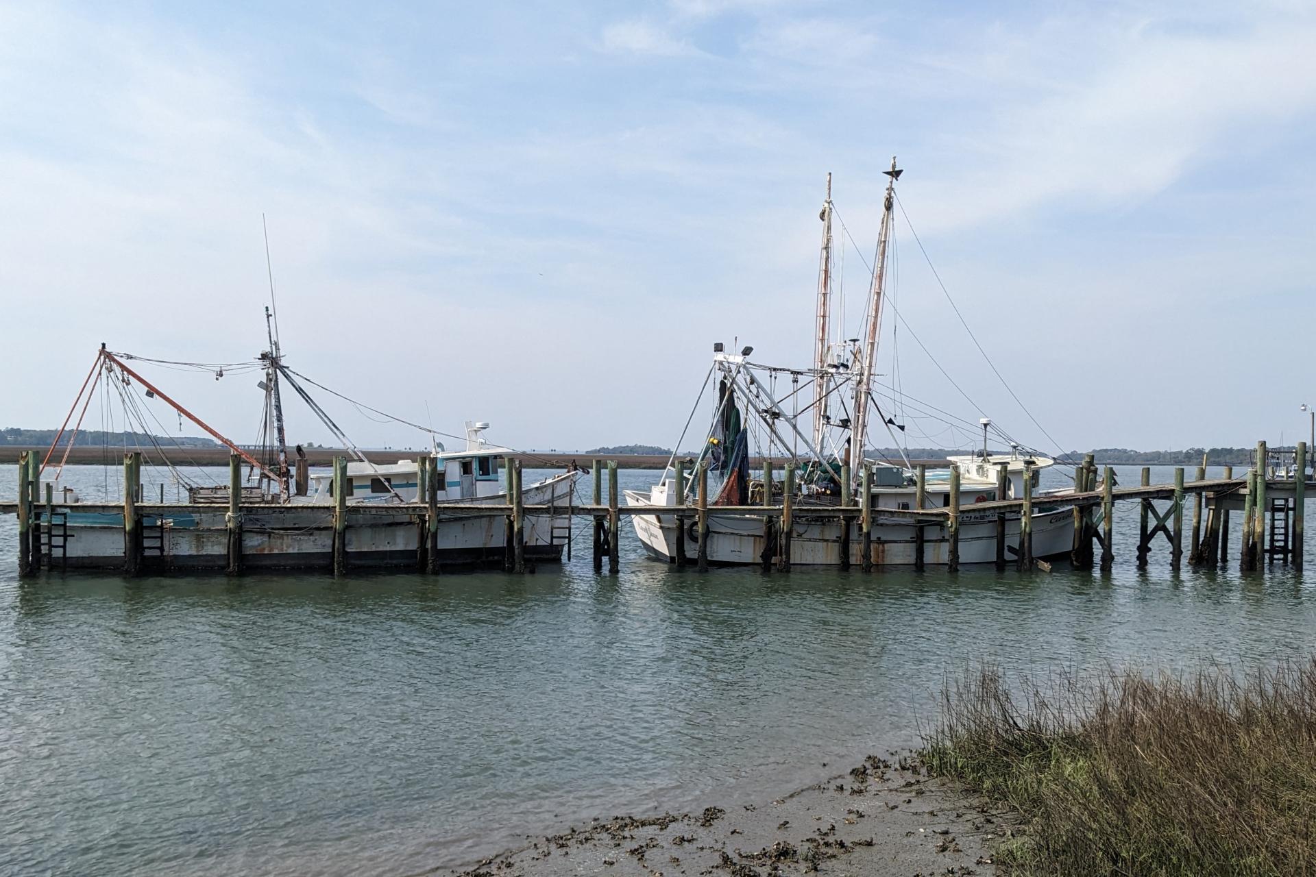 Two mid=sized boats next to a wooden pier