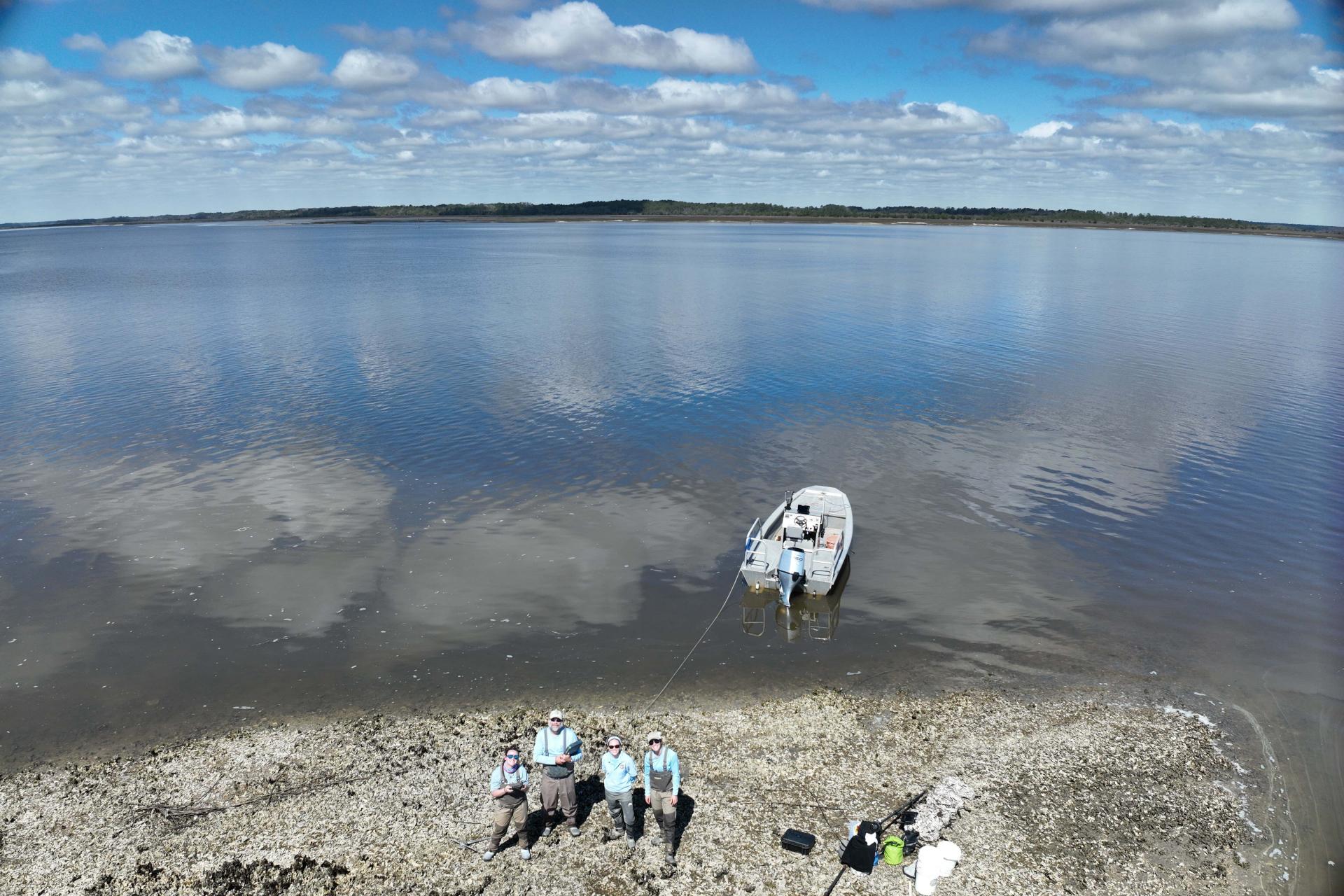 A bird eye's view of the team standing next to the water. There is a also boat.
